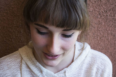 Close-up of woman wearing make-up against wall