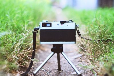 Close-up of camera on tripod amidst grass