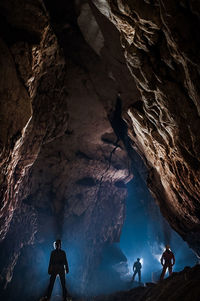 Rear view of silhouette people standing in cave