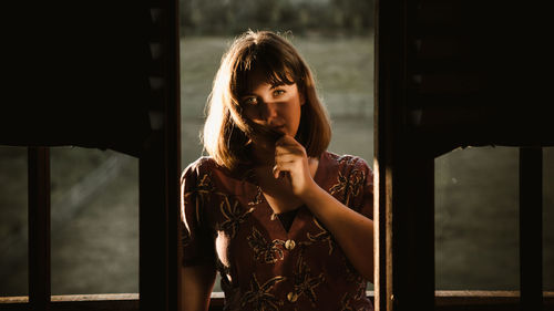 Portrait of young woman looking through window