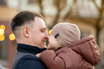 A happy father and three year old son hug in a city street. warm relationships between parents 