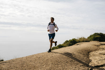 Full length of man running on shore against sky