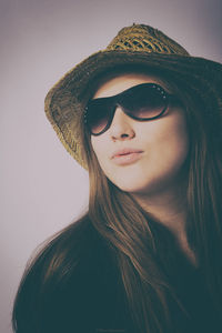 Close-up of young woman wearing sunglasses against gray background