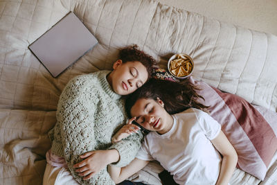 Directly above shot of female friends lying on bed at home