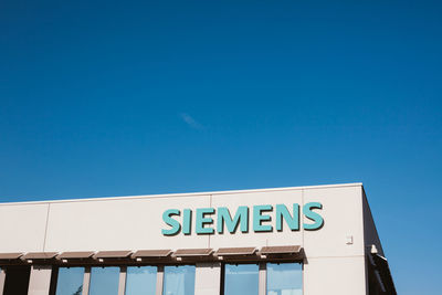 Low angle view of information sign against clear blue sky