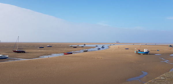 Scenic view of boats moored on beach against sky