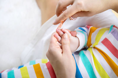 Mother cutting finger nails of baby at home