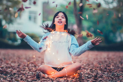 Close-up of smiling young woman throwing leaves