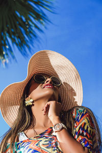 Low angle view of woman wearing sunglasses against clear sky