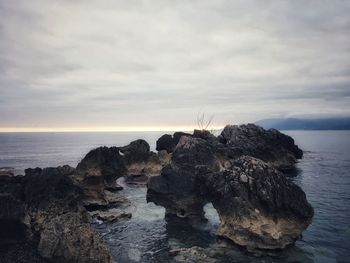 Rock formations on shore against sky