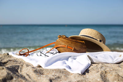  straw bag and hat on sand at beach against sky