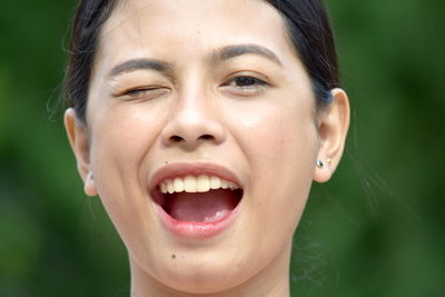 Close-up portrait of woman winking outdoors