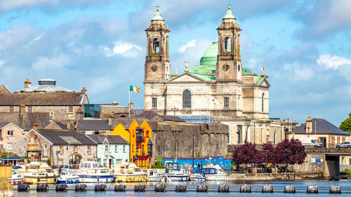 View of buildings in city against cloudy sky