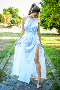 Full length of young woman standing against tree