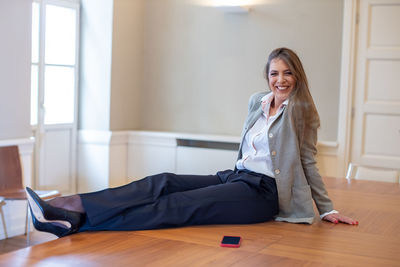 Portrait of smiling young woman sitting on hardwood floor