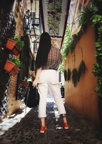 Rear view of woman walking by building