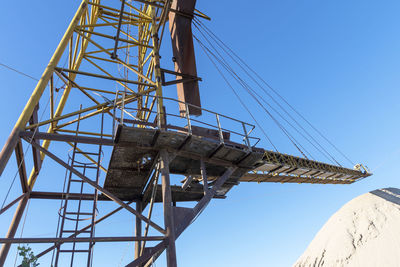 Low angle view of electricity pylon against clear blue sky