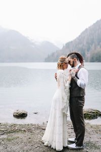 A loving married couple the bride and groom in suits celebrate wedding near the mountains and water