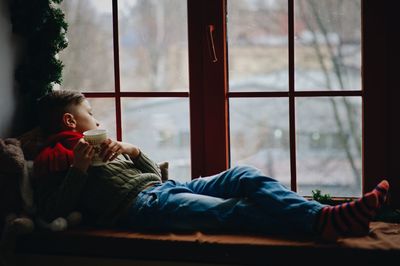 Boy sitting by window at home