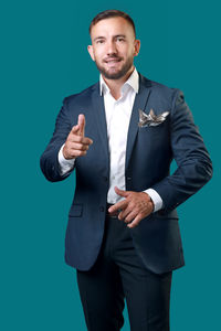 Portrait of businessman standing against blue background