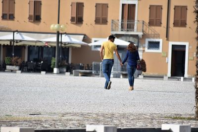 Rear view of people walking on street in city