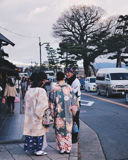 Rear view of people walking on street in city