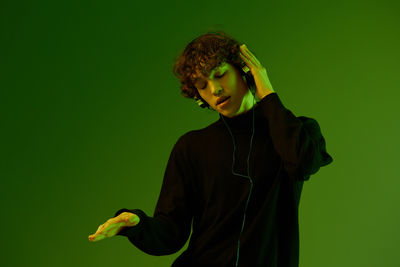 Young woman with arms crossed standing against yellow background