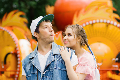 Happy couple in love having fun in an amusement park, eating lollipops person