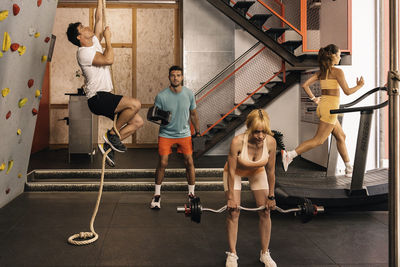 Group of young pro athletes performing different  workouts in the gym with a personal trainer.