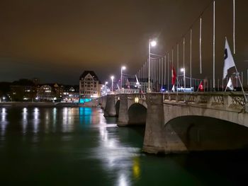 Bridge over river against sky in city at night