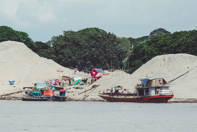 People on boat at beach against sky