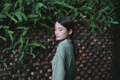 Young woman standing against brick wall at night