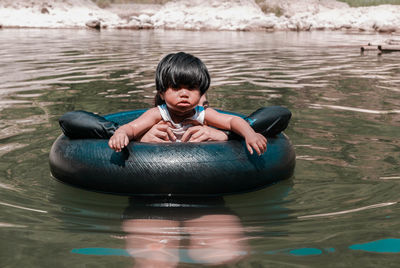 Girl with mother amidst inflatable ring swimming in lake