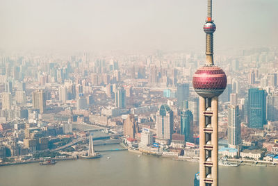 Communications tower in city against sky