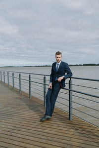 Portrait of handsome man leaning on railing against sea