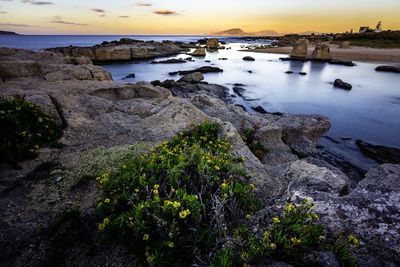 High angle view of rocks and sea against sky during sunset