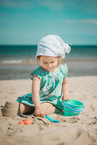 Full length of girl making sandcastles while sitting on beach