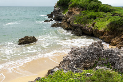Rocks on shore by sea against sky