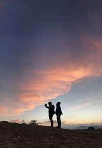 Full length of men standing on land against sky during sunset