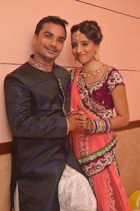 Portrait of couple in traditional clothing standing against wall