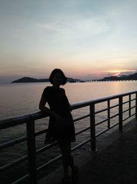 Man looking at sea against sky during sunset
