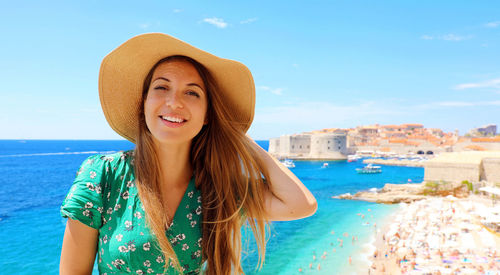 Portrait of smiling young woman against sea against sky