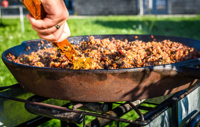Close-up of man preparing food on barbecue grill in yard