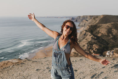 Young woman wearing sunglasses standing on beach