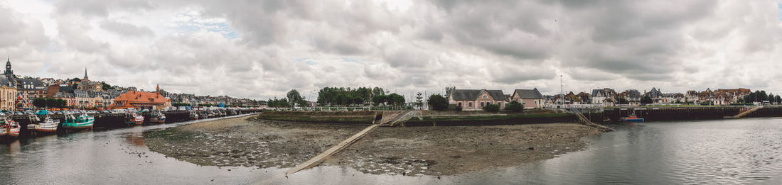 Panoramic view of sea and buildings against cloudy sky