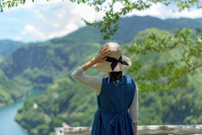 Rear view of woman standing against mountain range