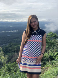 Portrait of smiling young woman standing against sky