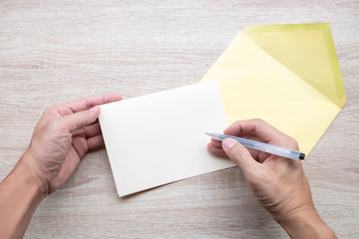 Low section of person holding paper on table