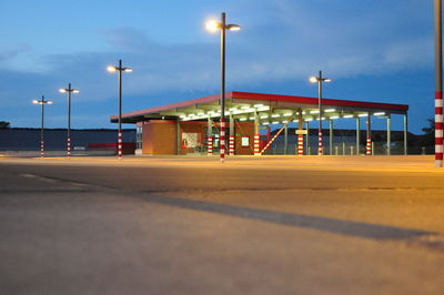 Illuminated empty parking lot against sky at dusk