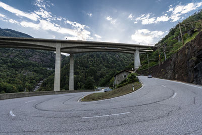 Empty road by bridge in city against sky